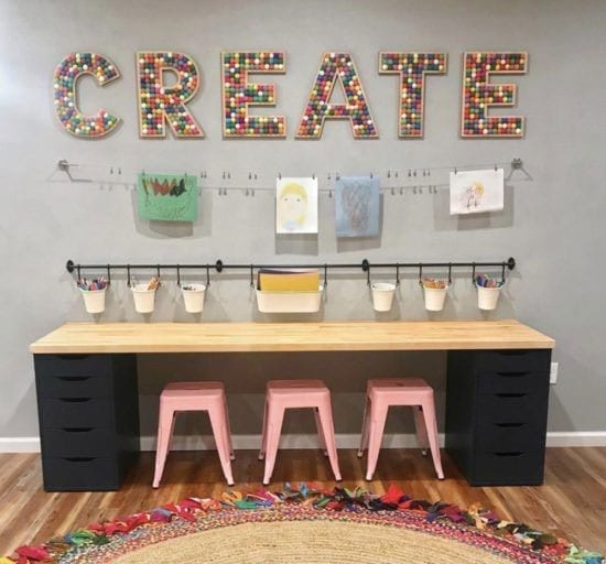 A child's homeschool classroom workstation created using IKEA countertops, shelving, stools, and a homemade rug.