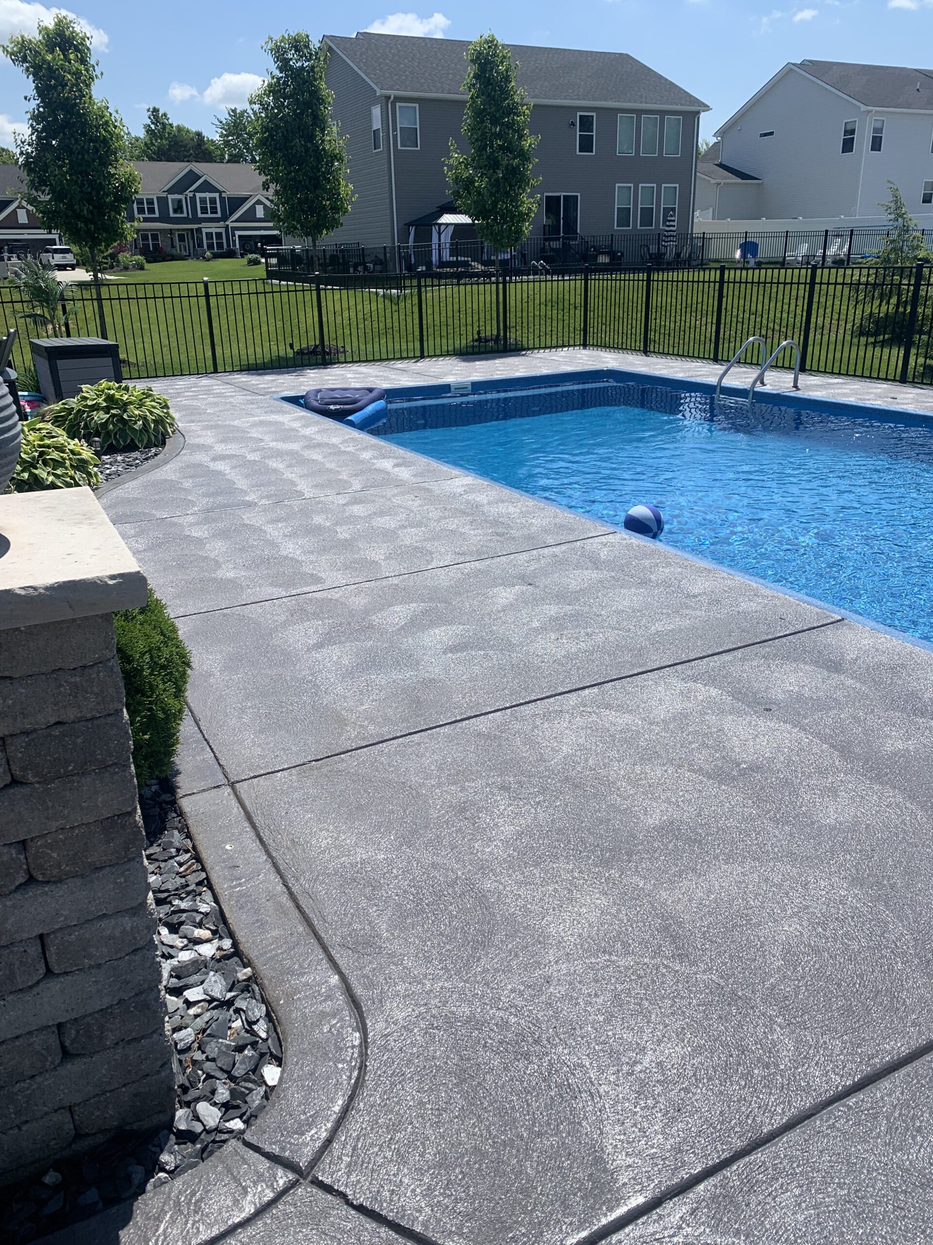 Modern gray stained swirl finish concrete pool deck.