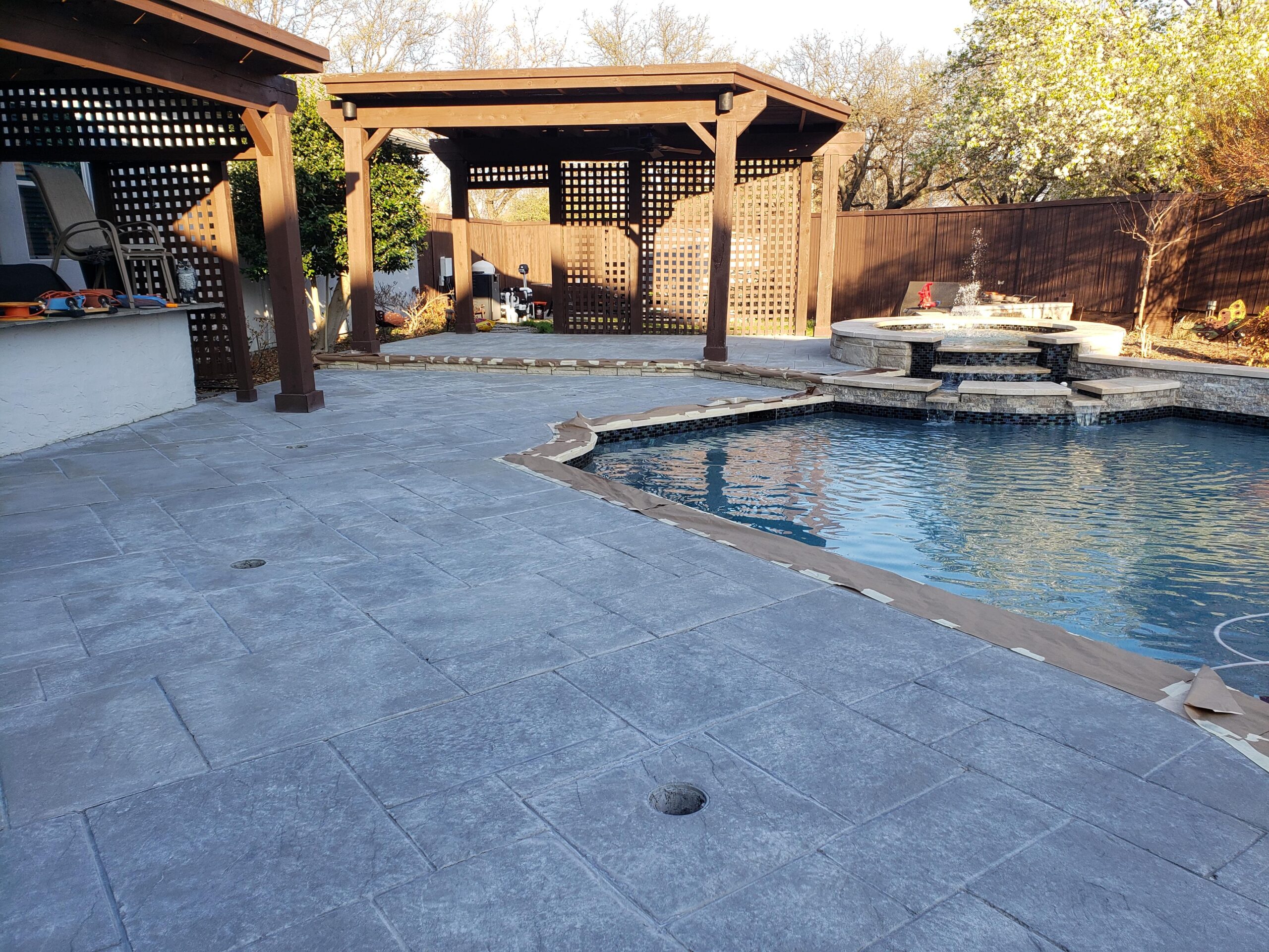 After photo of a stylishly transformed stamped concrete pool deck, stained in elegant gray and sealed with EasySeal