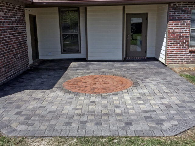 A circular paver design on a charcoal Portico stained patio with an inner circle stained in terracotta.