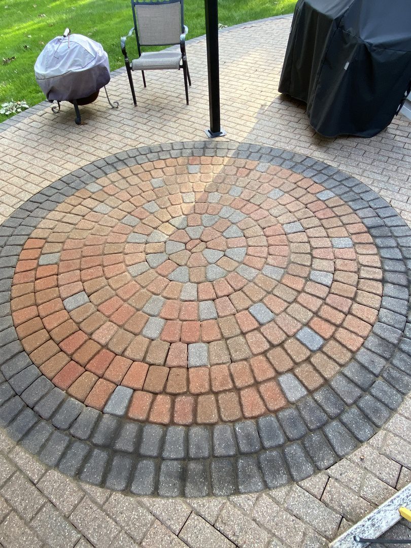 Circular terracotta, russet & silver gray stained paver patio design with contrasting charcoal border.