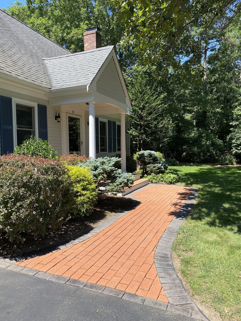 A stunning terracotta Portico stained paver walkway with a warm, earthy hue, featuring an outer edge stained with charcoal Portico paver stain.