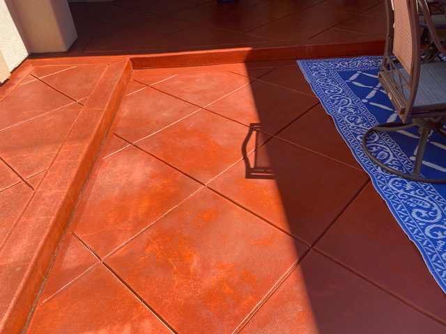 An image showing a Terracotta stained concrete patio with a mishap. The stain appears to have been applied too heavily, resulting in uneven coverage and an unsightly finish. This serves as an example of the importance of proper stain application techniques and surface preparation before staining concrete.