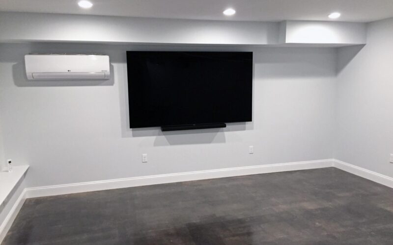Renovated basement room with a TV, showcasing the gleaming floor finish