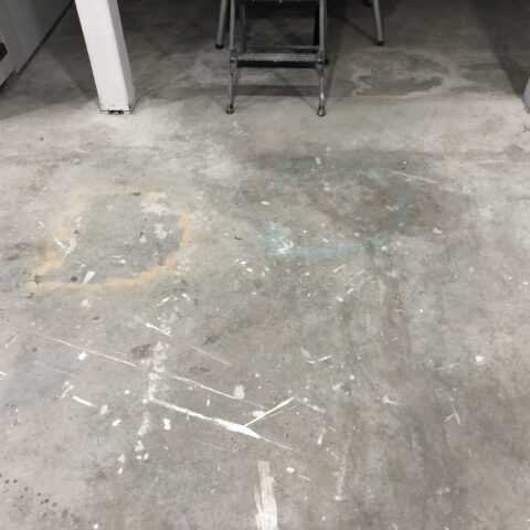 Basement floor with old stains, spray paint and overspray on it