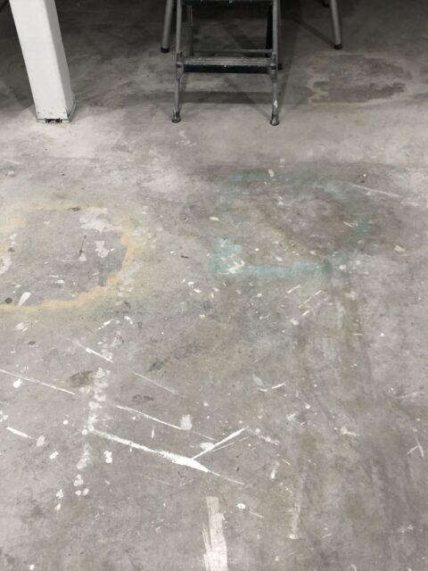 Basement floor with old stains, spray paint and overspray on it