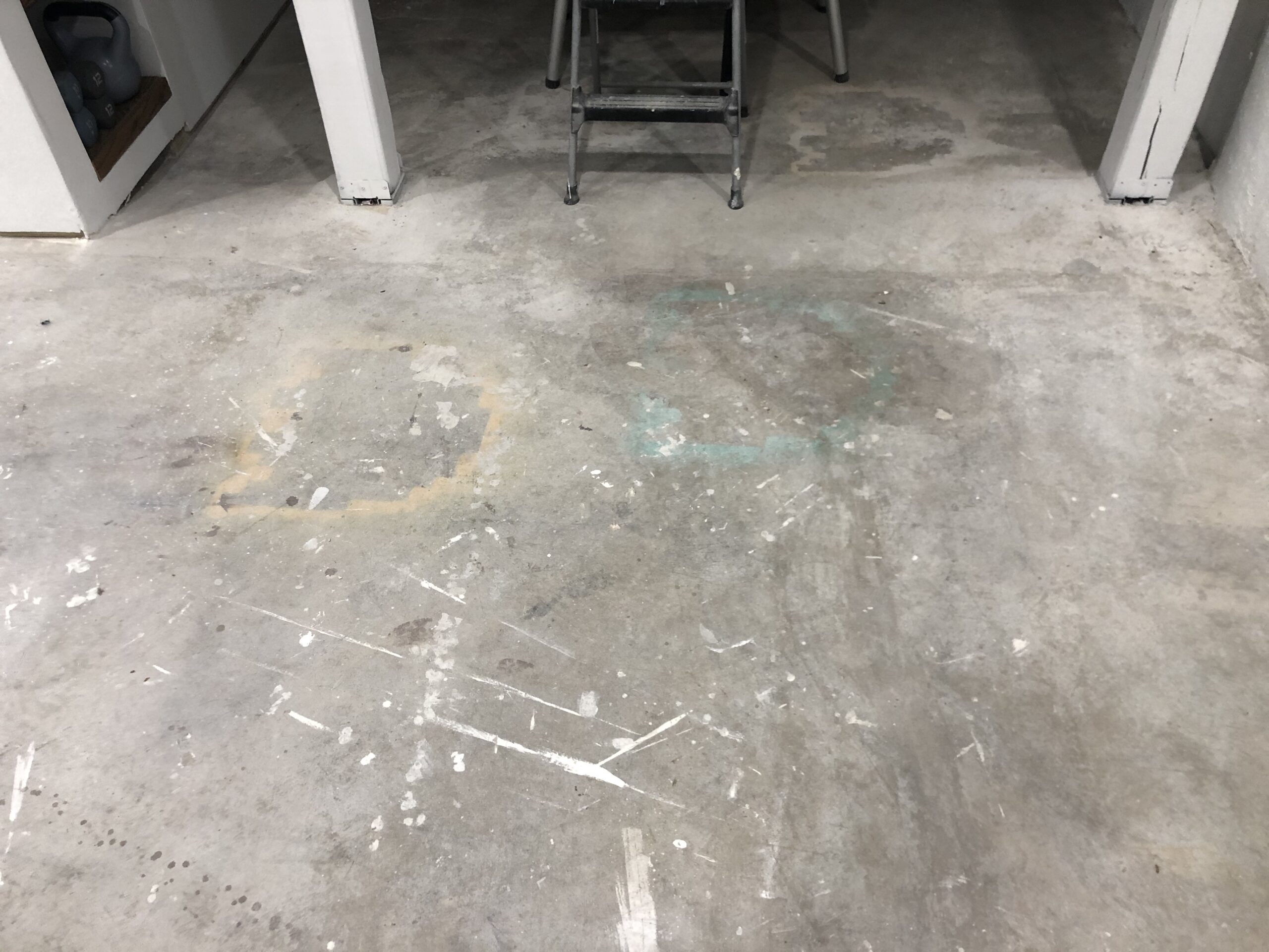 Basement floor with old stains spray paint and overspray on it scaled