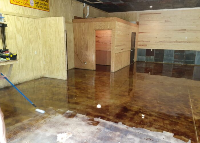 Roller applying high gloss EasySeal sealer on coffee brown acid stain concrete garage floor