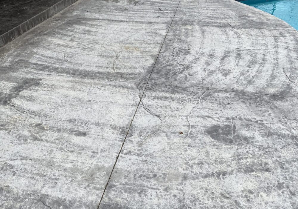 Damaged dark charcoal stamped concrete before restoration