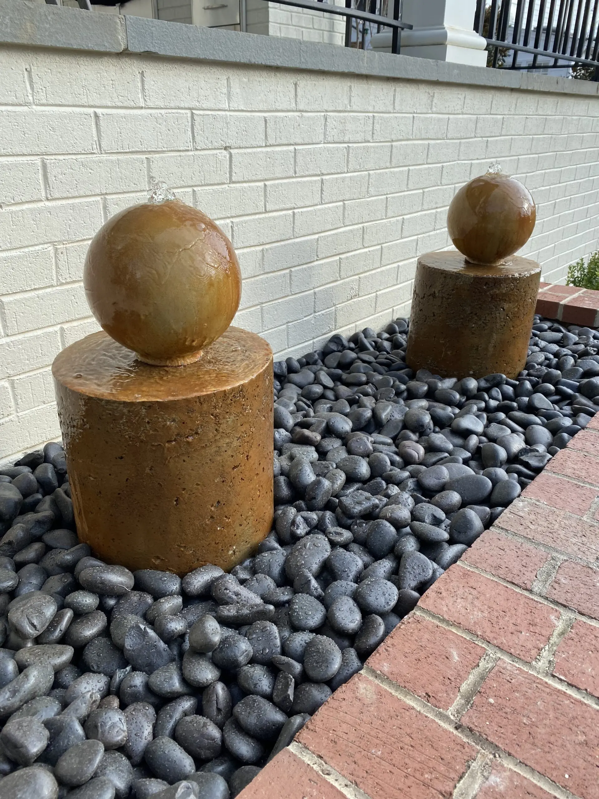 The completed DIY concrete fountain, beautifully stained with EverStain's Malayan Buff and Desert Amber, standing as a vibrant centerpiece against the patio's brick background