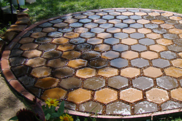 Close-up of a wet circular patio design with hexagonal pavers stained in Driftwood and Yukon Gold