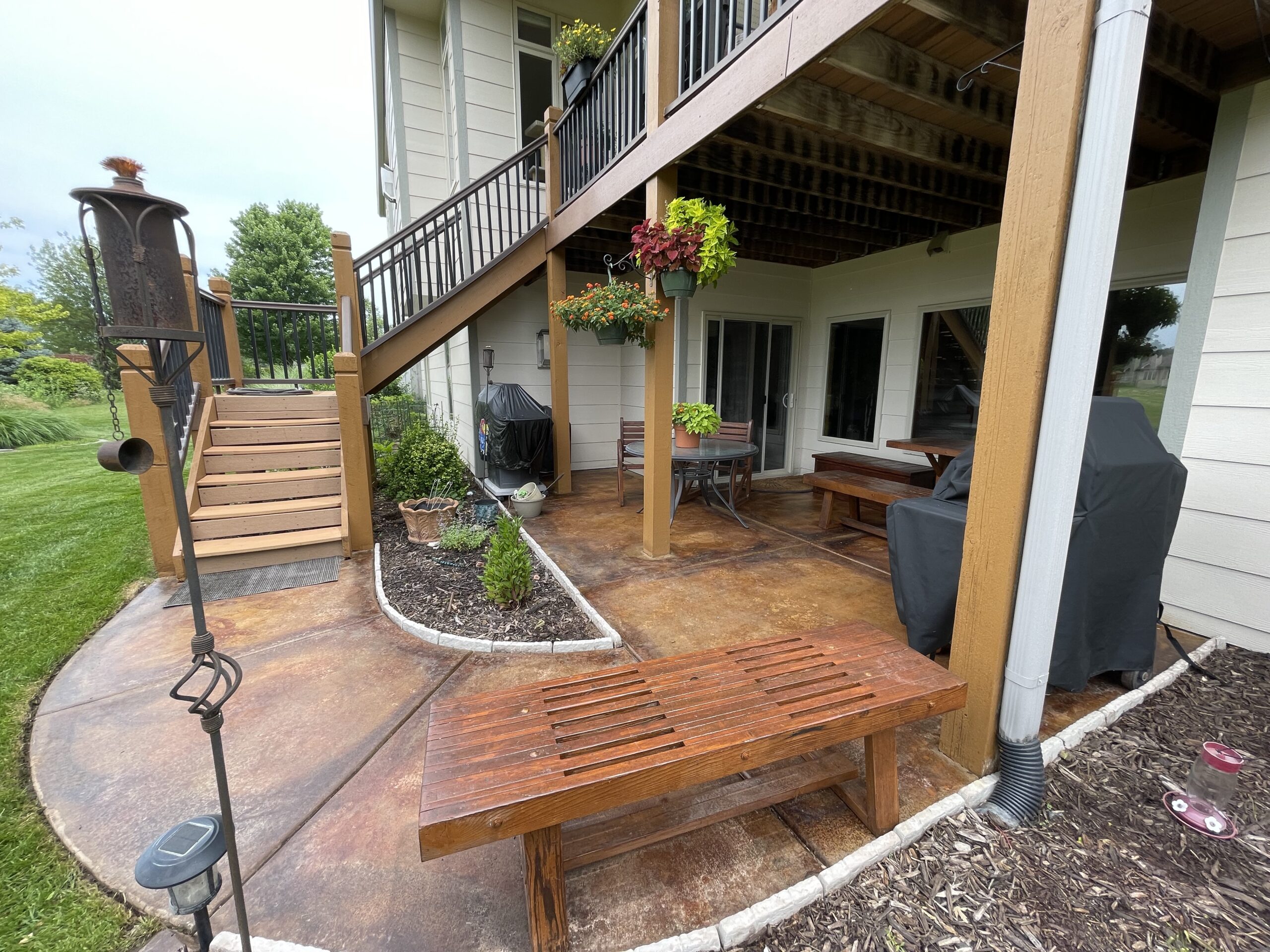 Transformed round patio showcasing a rich blend of Malayan Buff, Desert Amber, and English Red acid stains, complementing the refinished redwood furniture