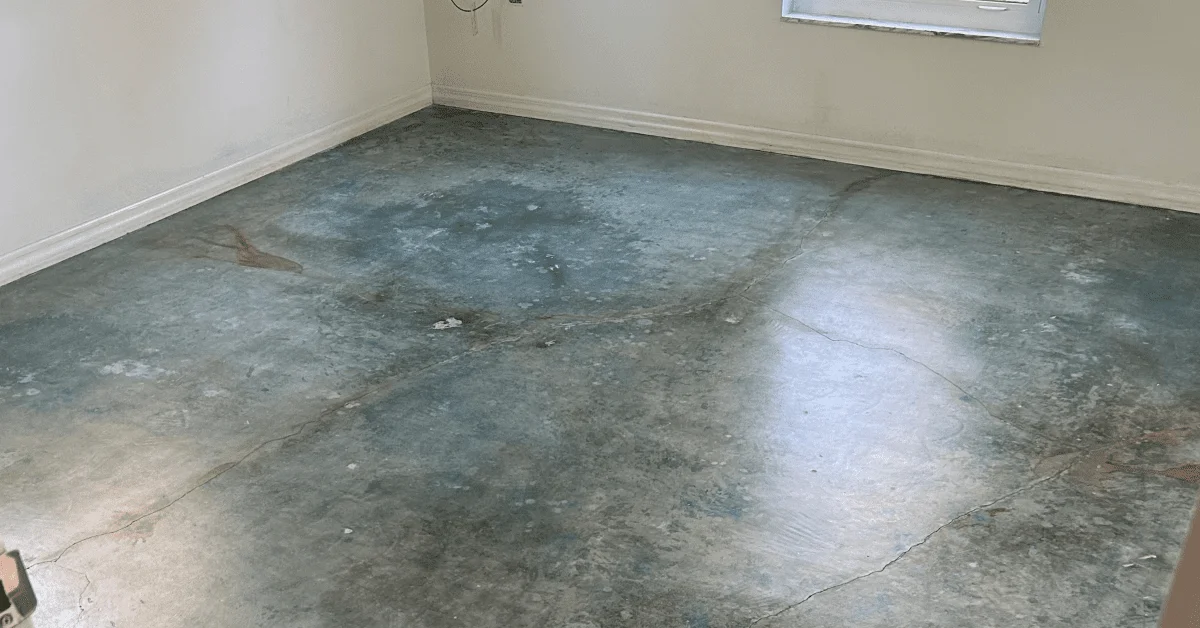 Empty room with a concrete floor treated with an Azure Blue acid stain, showing a varied, natural stone-like finish with hints of blue hues.