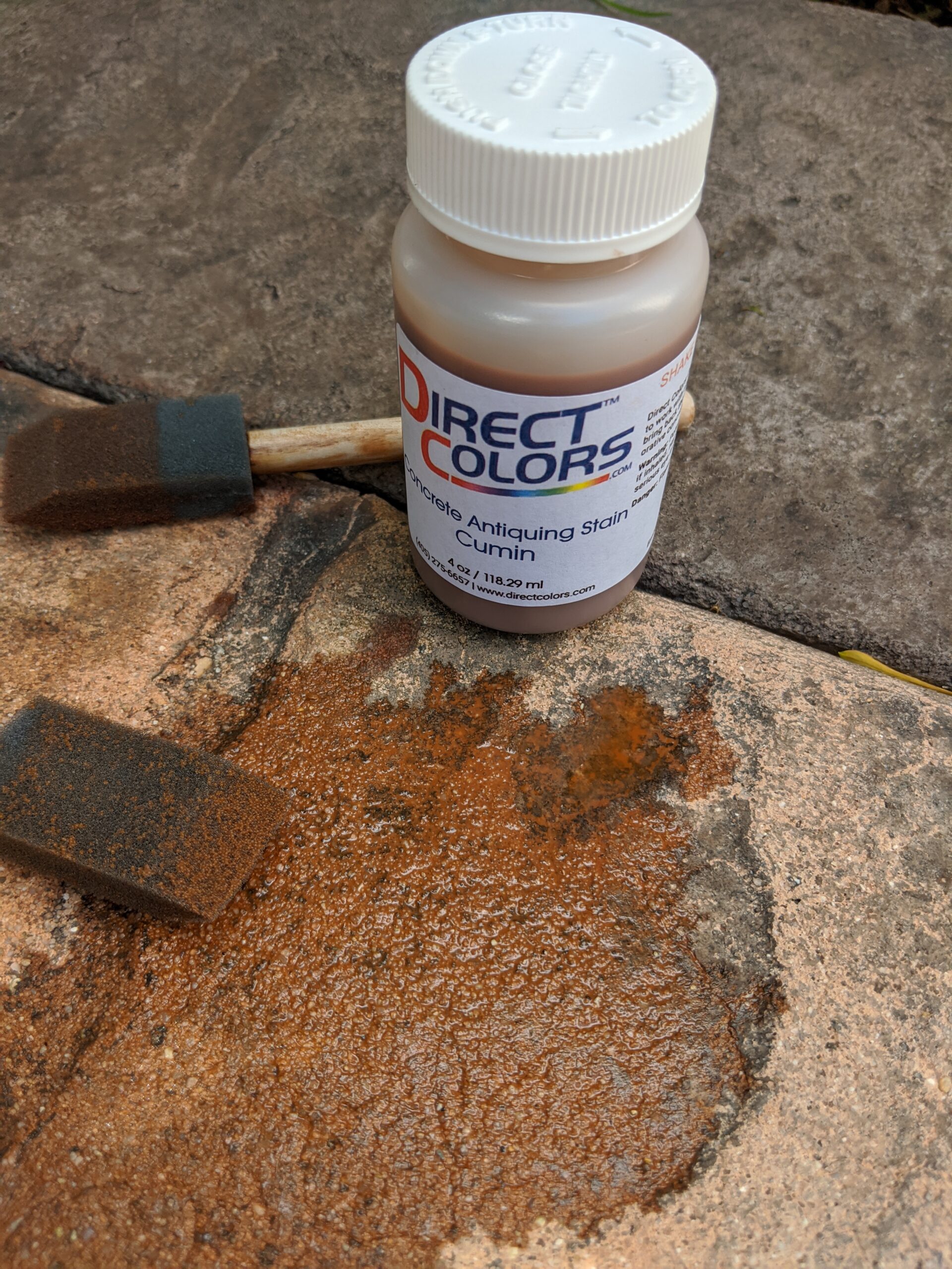 Testing various Antiquing stain colors on a faded stamped concrete surface to find the perfect match