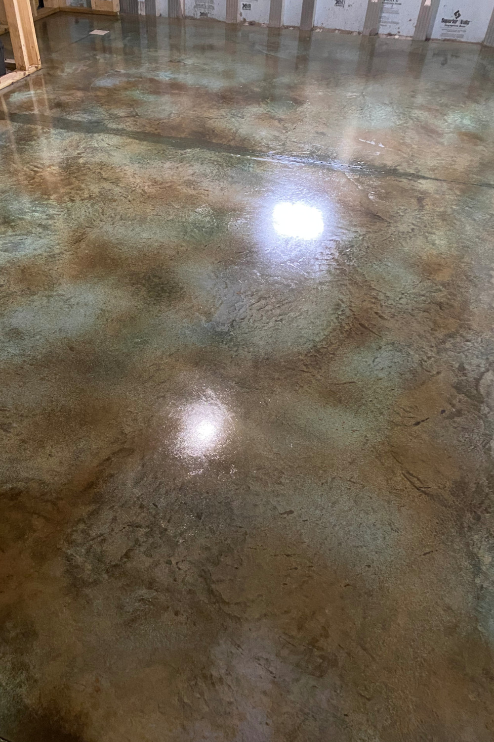 A photo of a concrete floor with the first coat of sealer applied, showing a glossy surface