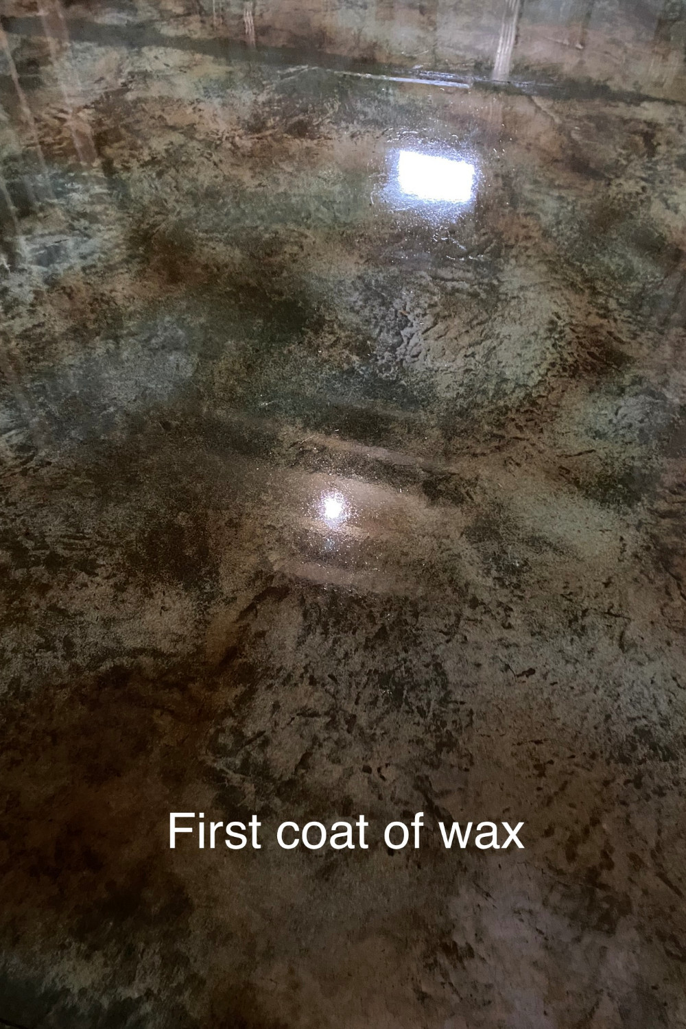 A photo of a concrete floor with the first coat of concrete floor wax applied, showing a glossy and protected surface