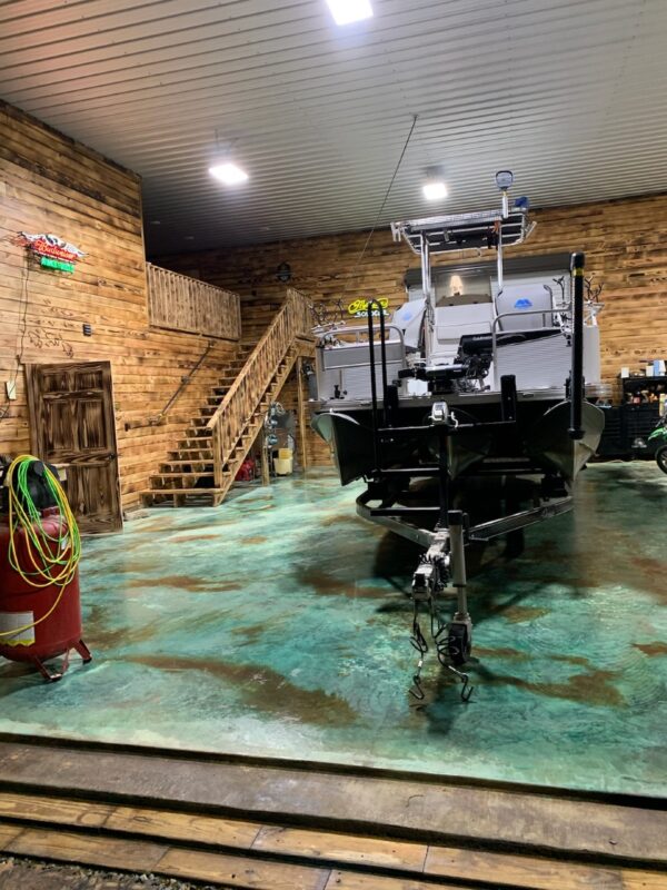 A dry azure blue and shifting sand stained concrete garage floor with a boat parked on top, showcasing the practicality and aesthetic appeal of the transformation.