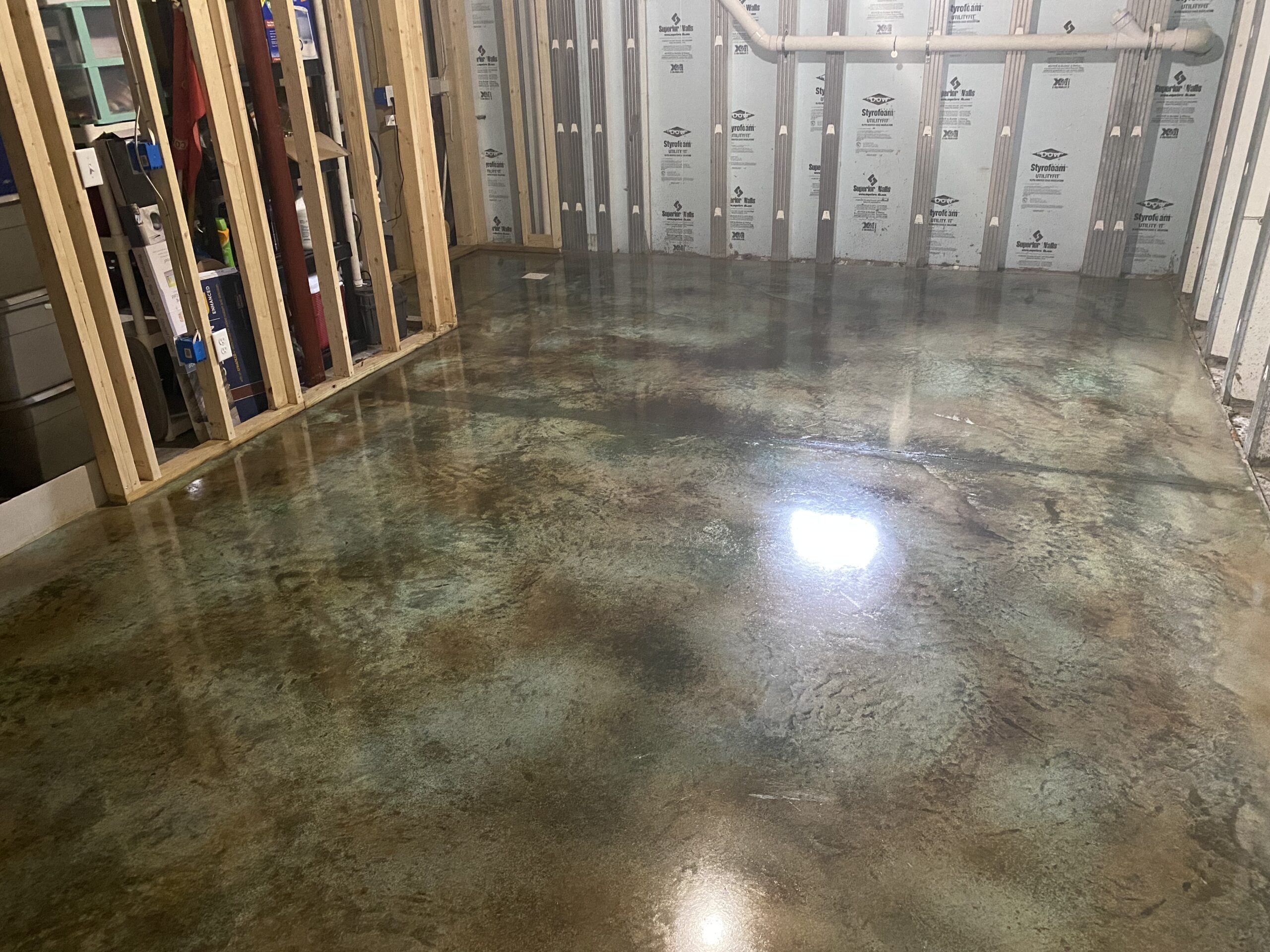 A photo of a completed acid stained concrete basement floor, displaying the unique multi-layered color effect on the surface
