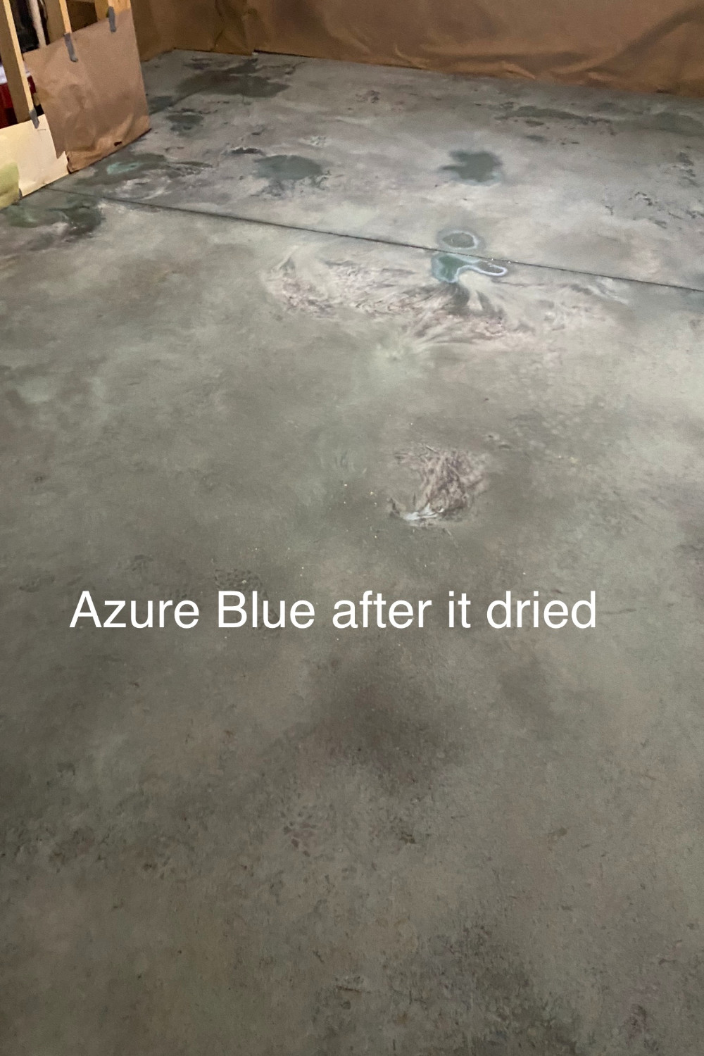A photo of a concrete basement floor with a dried Azure Blue acid stain covering the surface