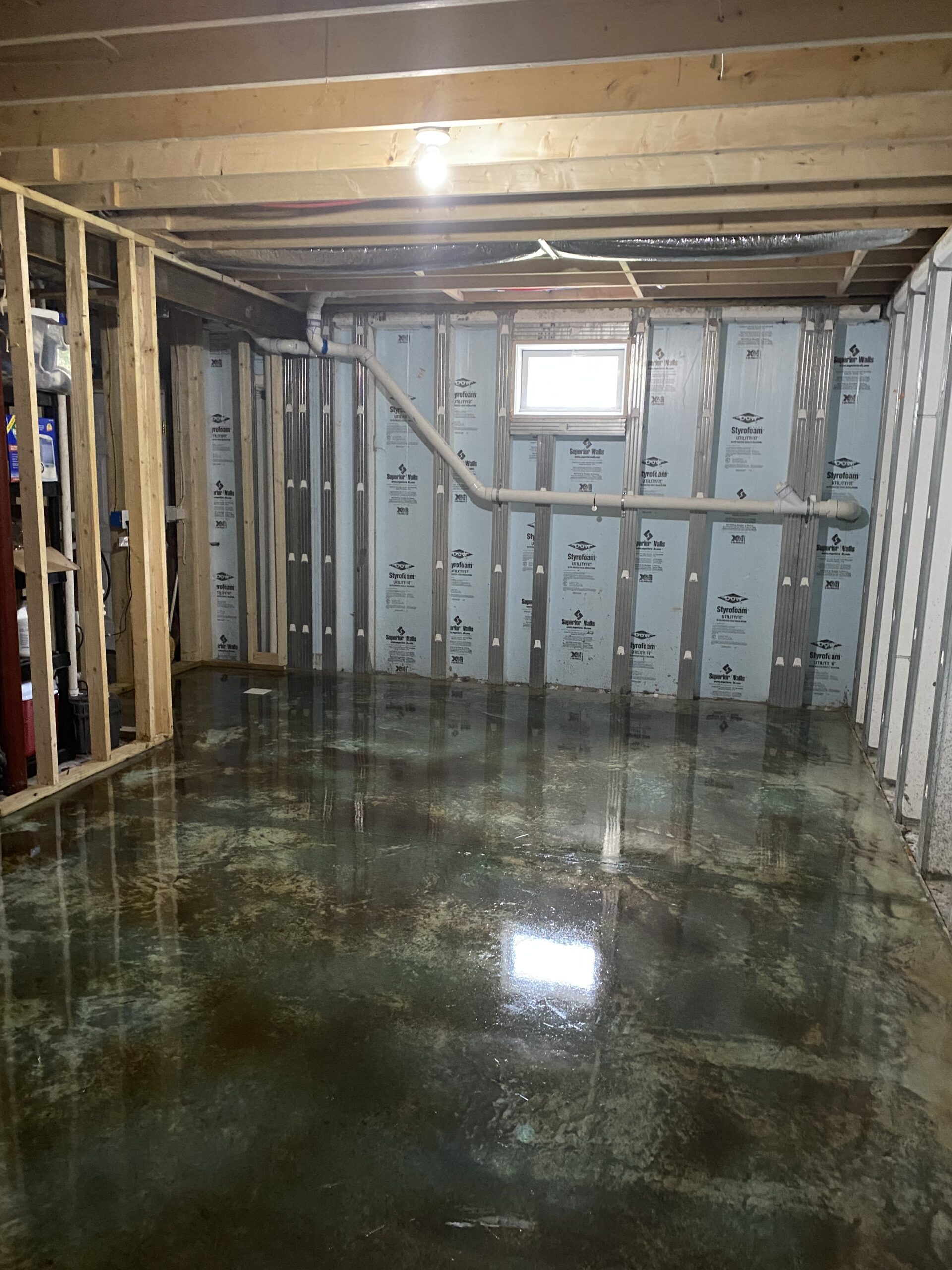 A photo of a wet concrete basement floor with the acid stain neutralized and rinsed, showing the final multi-layered color effect on the surface.