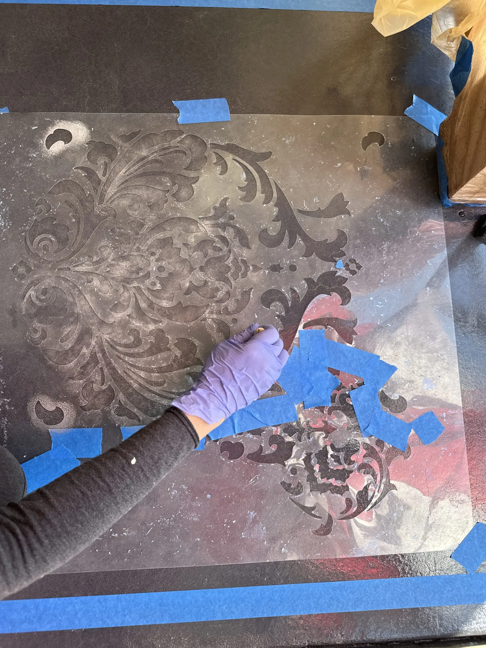 Applying an elegant Damask stencil onto the sealed, stained concrete floor.