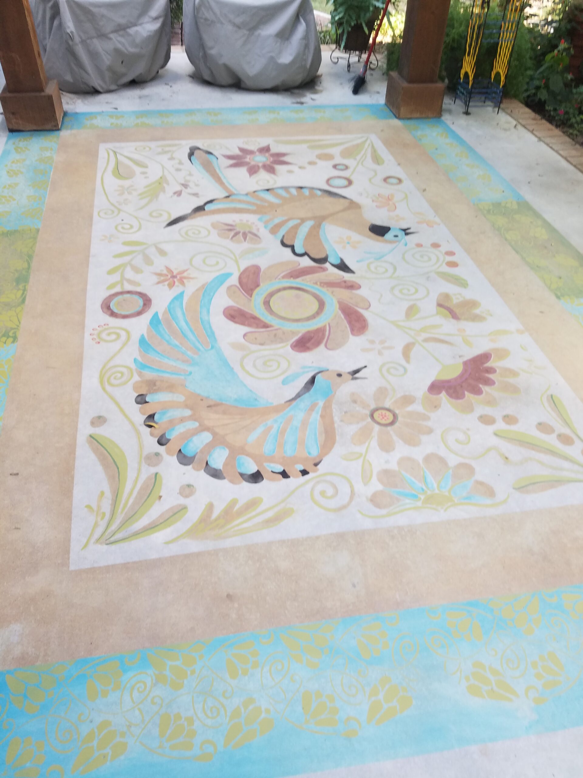 Concrete porch floor enhanced with a custom bird stencil design using DecoGel acid stains to emulate a decorative rug