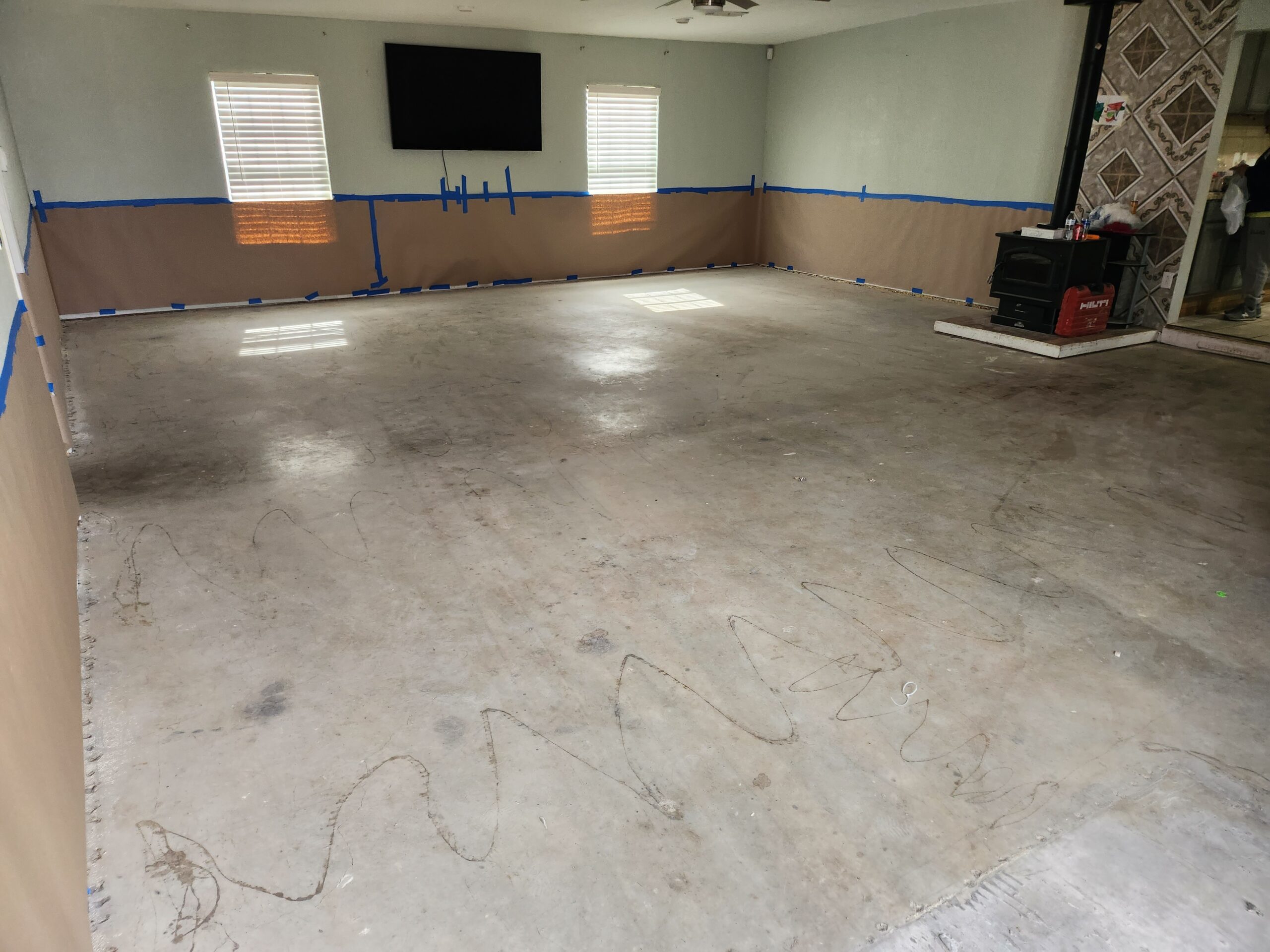 Empty living room with an unfinished concrete floor after removing carpets