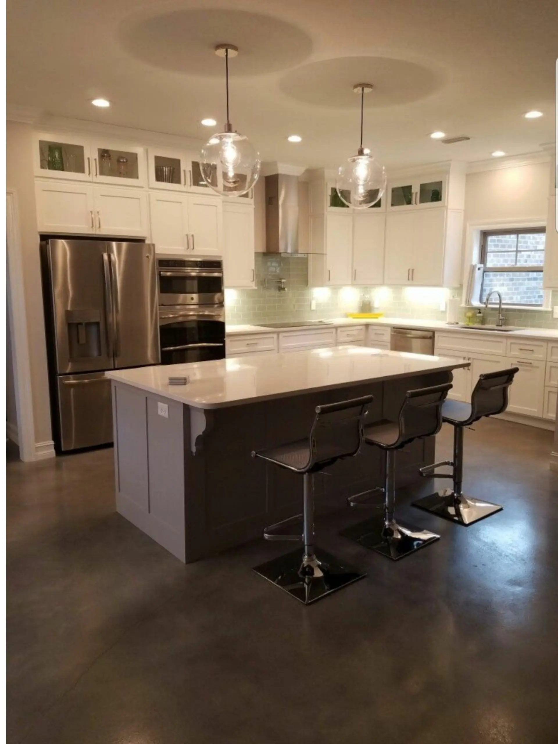 Modern kitchen with white cabinets, stainless steel appliances, and a concrete floor stained with light slate, stormy gray, and charcoal Vibrance dye