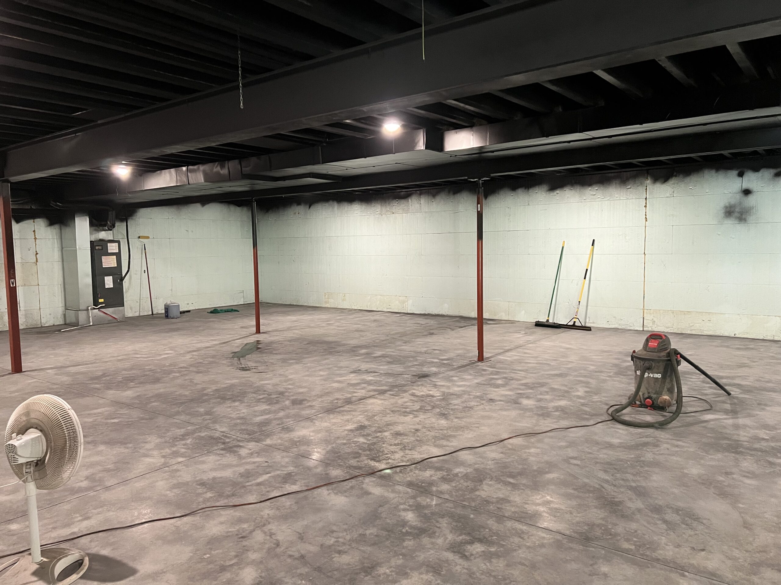 An image showing a concrete basement floor prepped for AquaTint application, having undergone power washing, stripping, and sanding