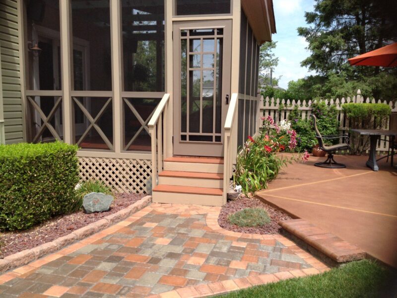 Russet Antiquing stained smooth, scored concrete pool deck with a multicolored paver walkway and home deck