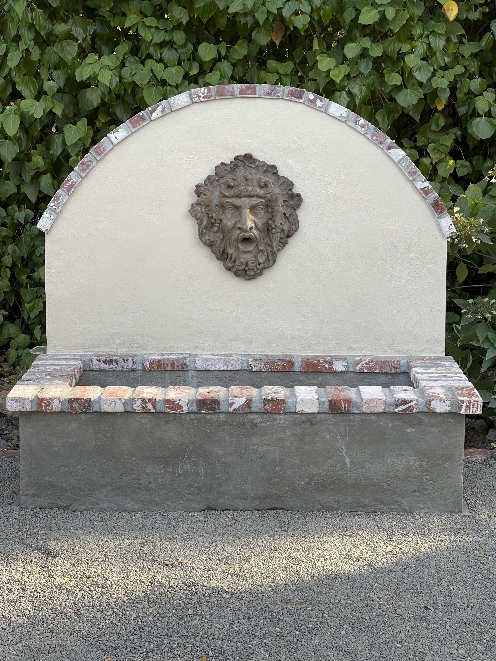 An unfinished concrete wall fountain, with a rough grey surface