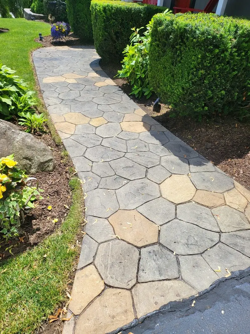 Stamped concrete walkway with a blend of black, café royale, Yukon gold, and goldenrod stains creating a honeycomb pattern