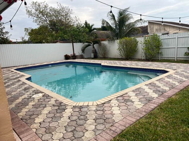Faded multicolor pavers surrounding a swimming pool