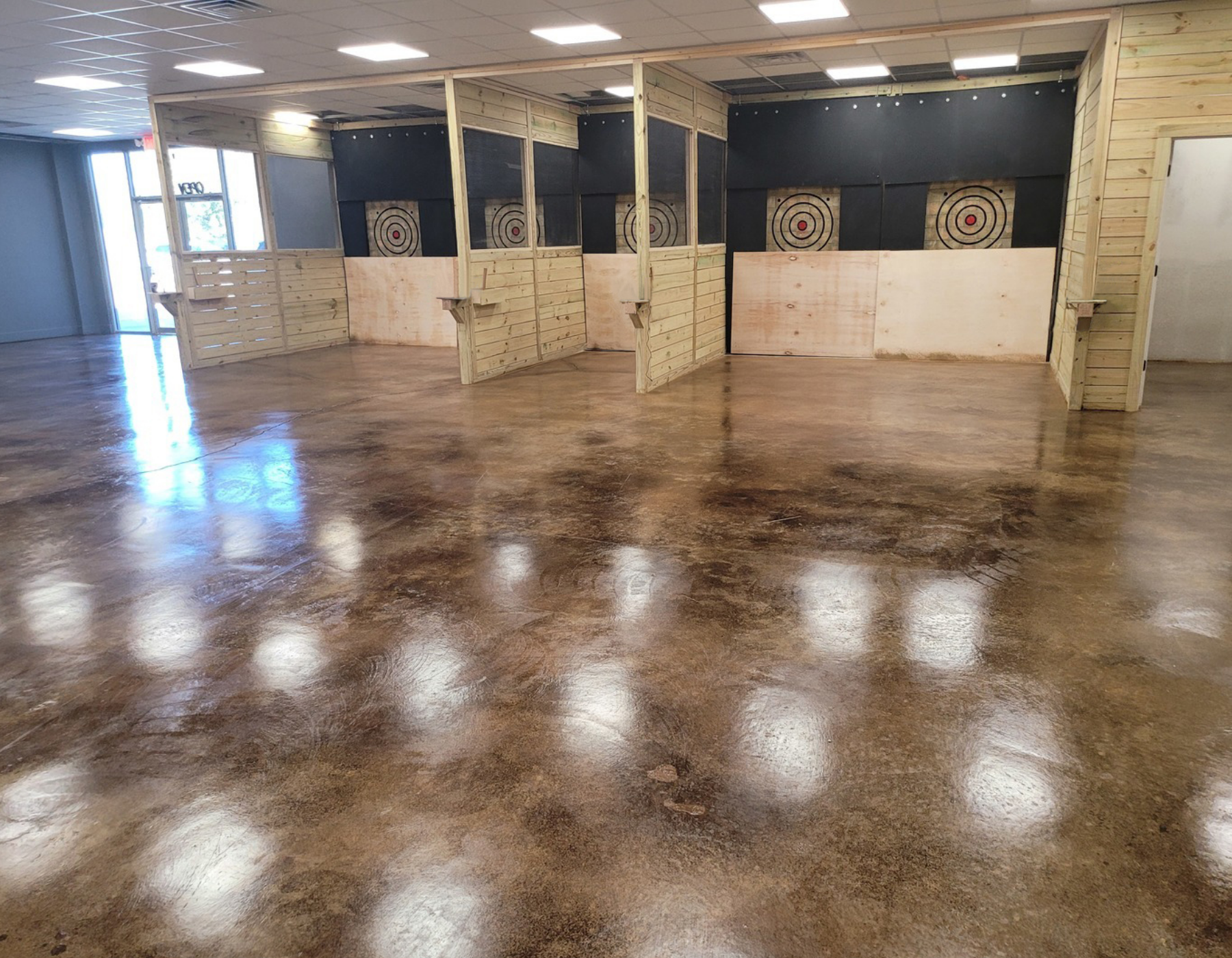 Brown acid stained concrete floor in an axe-throwing bar