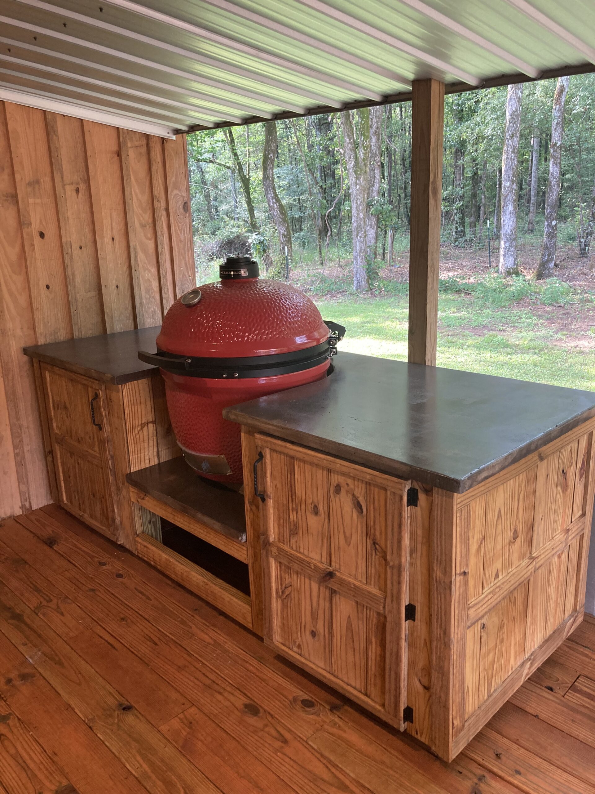 Concrete countertop perched on a rustic wood base featuring a round red BBQ with its lid
