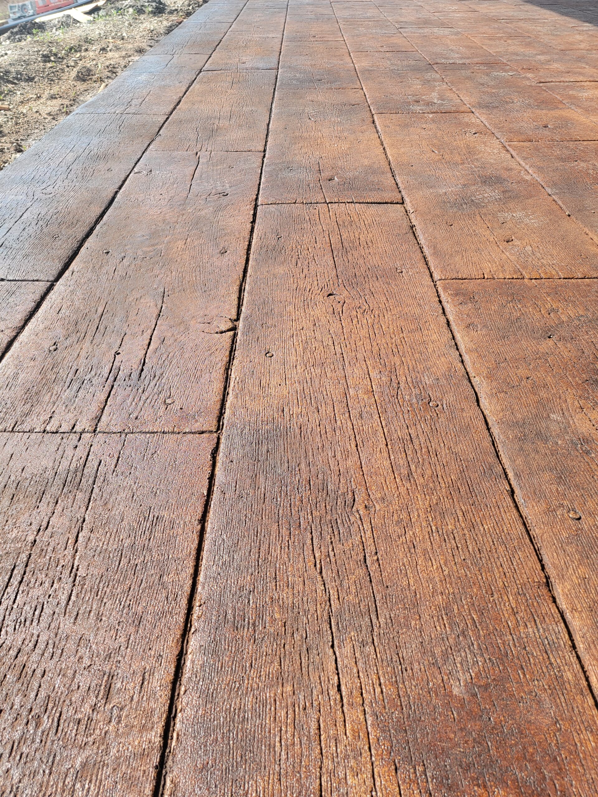 Finished and sealed faux wood-stamped concrete patio, displaying a realistic wood look