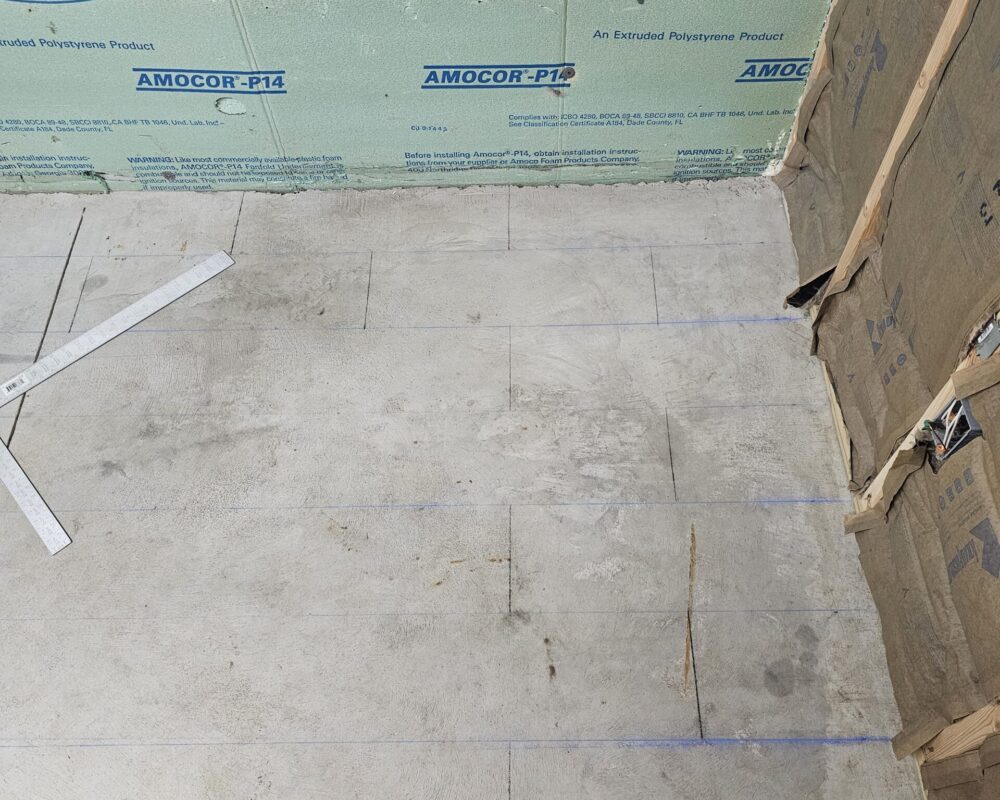 A chalk line being used to map out the future tile design on the concrete floor