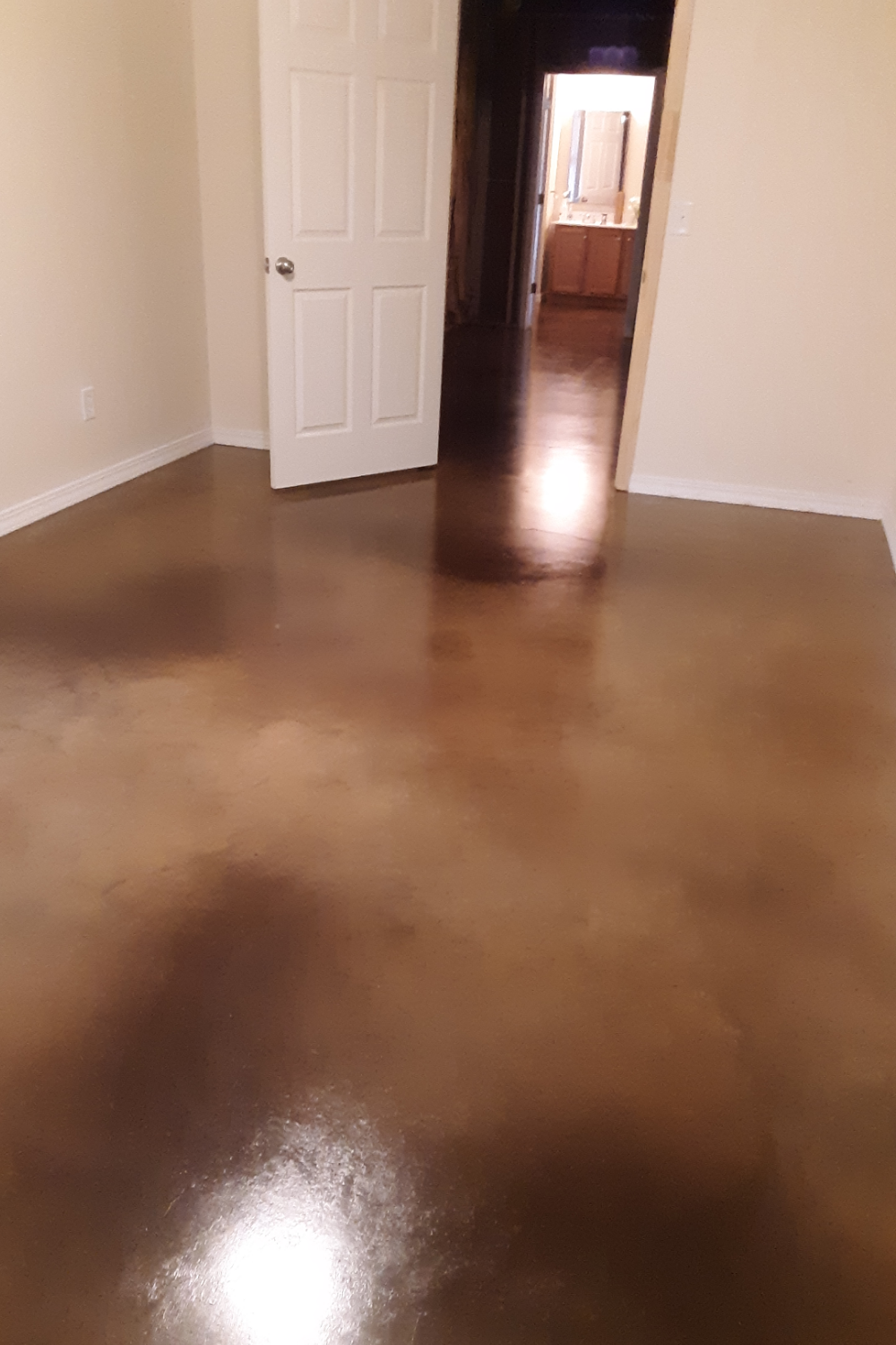 A finished basement floor with a rich, glossy stain in warm brown tones, featuring a smooth and polished finish