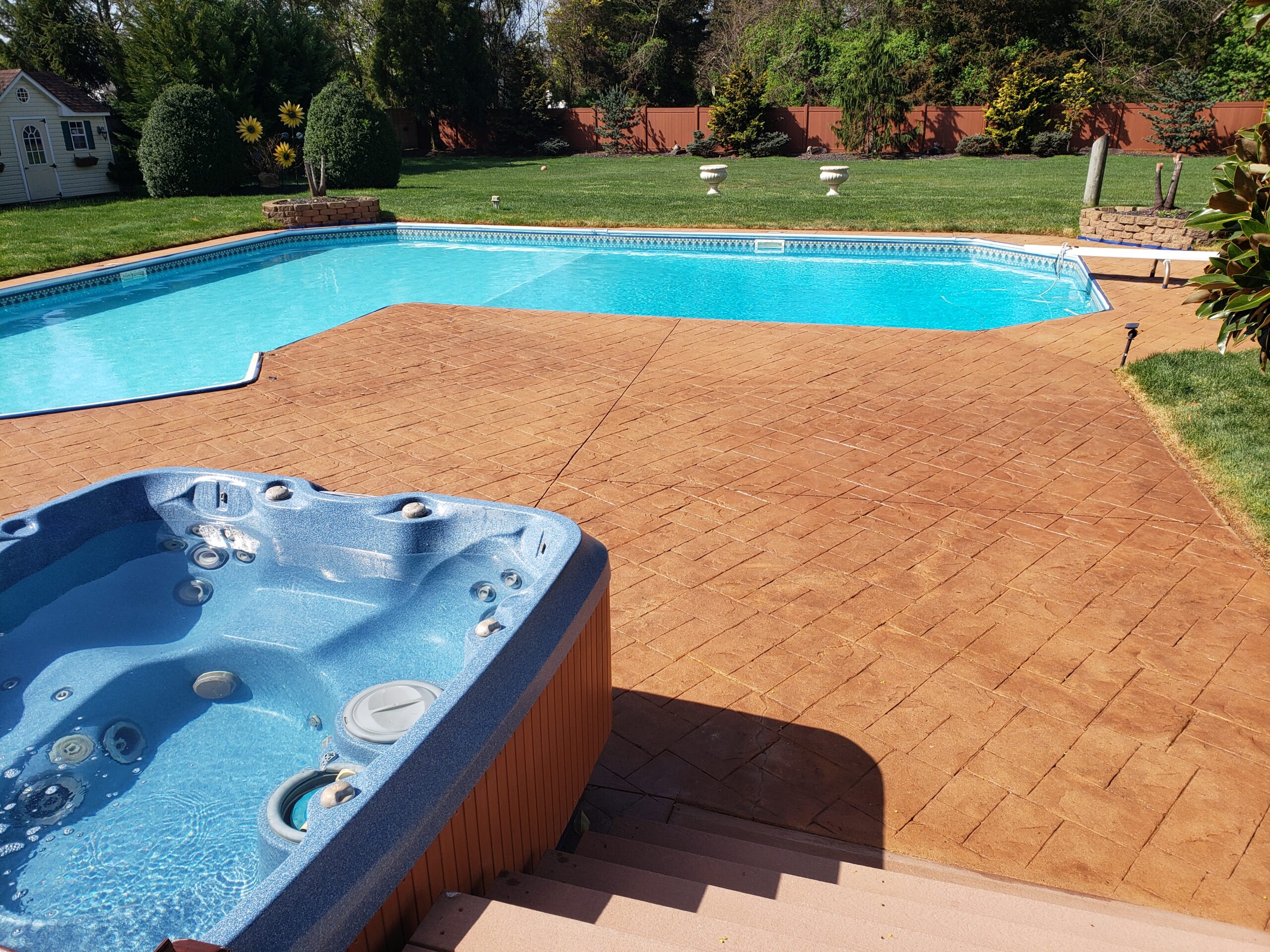 Post-transformation photo of the stamped concrete pool deck, now revitalized with Cumin Antiquing Stain and Satin EasySeal