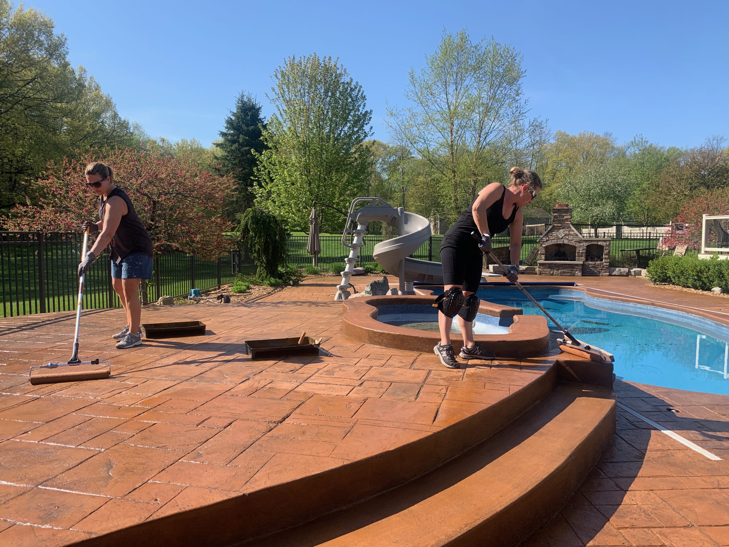 Two female customers diligently applying the Yukon Gold EasyTint second coat to a stamped concrete deck