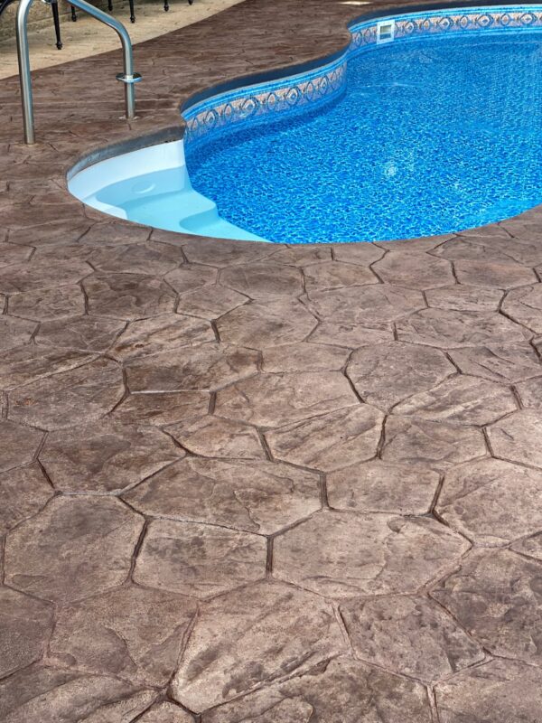 Pre-stain photo of the 13-year-old stamped concrete pool deck, showing visible wear, stains, and old sealer.