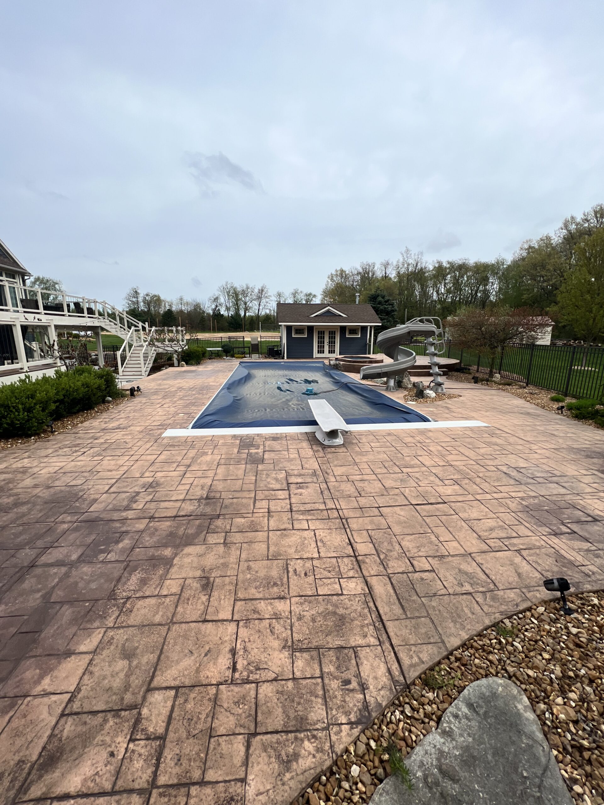 A faded stamped concrete pool deck, showing signs of wear and weathering