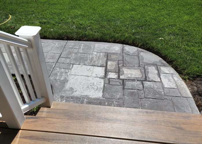 Close-up view of the worn-out stamped concrete sidewalk before renovation