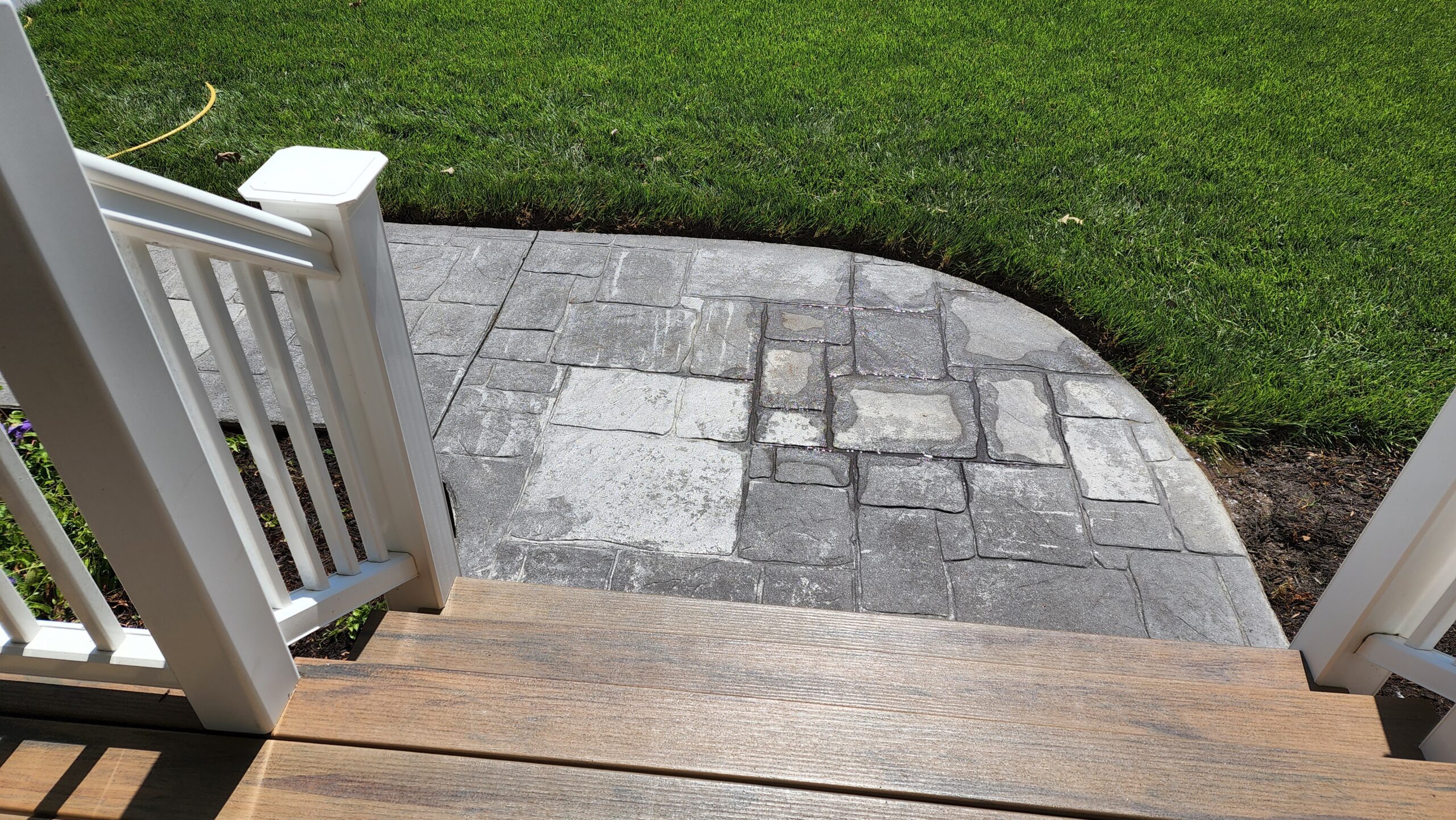 Close-up view of the worn-out stamped concrete sidewalk before renovation