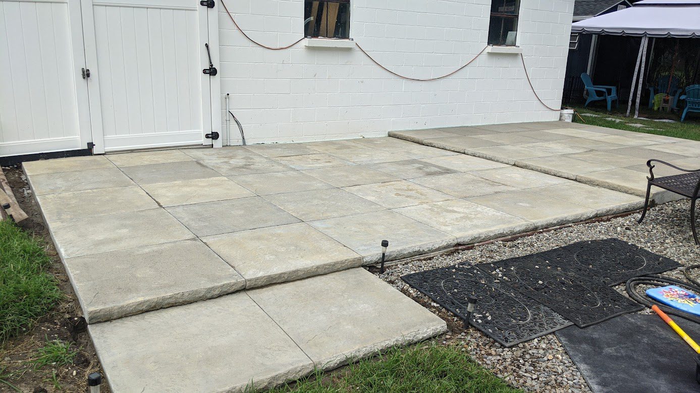 Image showcasing the raw, untouched state of a patio made of 36-inch hand-poured squares, each one stamped to mimic slate, before the application of silver gray concrete stain