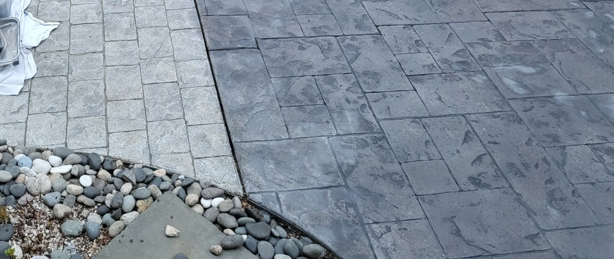 Stark contrast between a stained and sealed concrete patio section with a gray Antiquing stain and satin finish, and the adjacent untreated section, which retains a dull and unrefined appearance