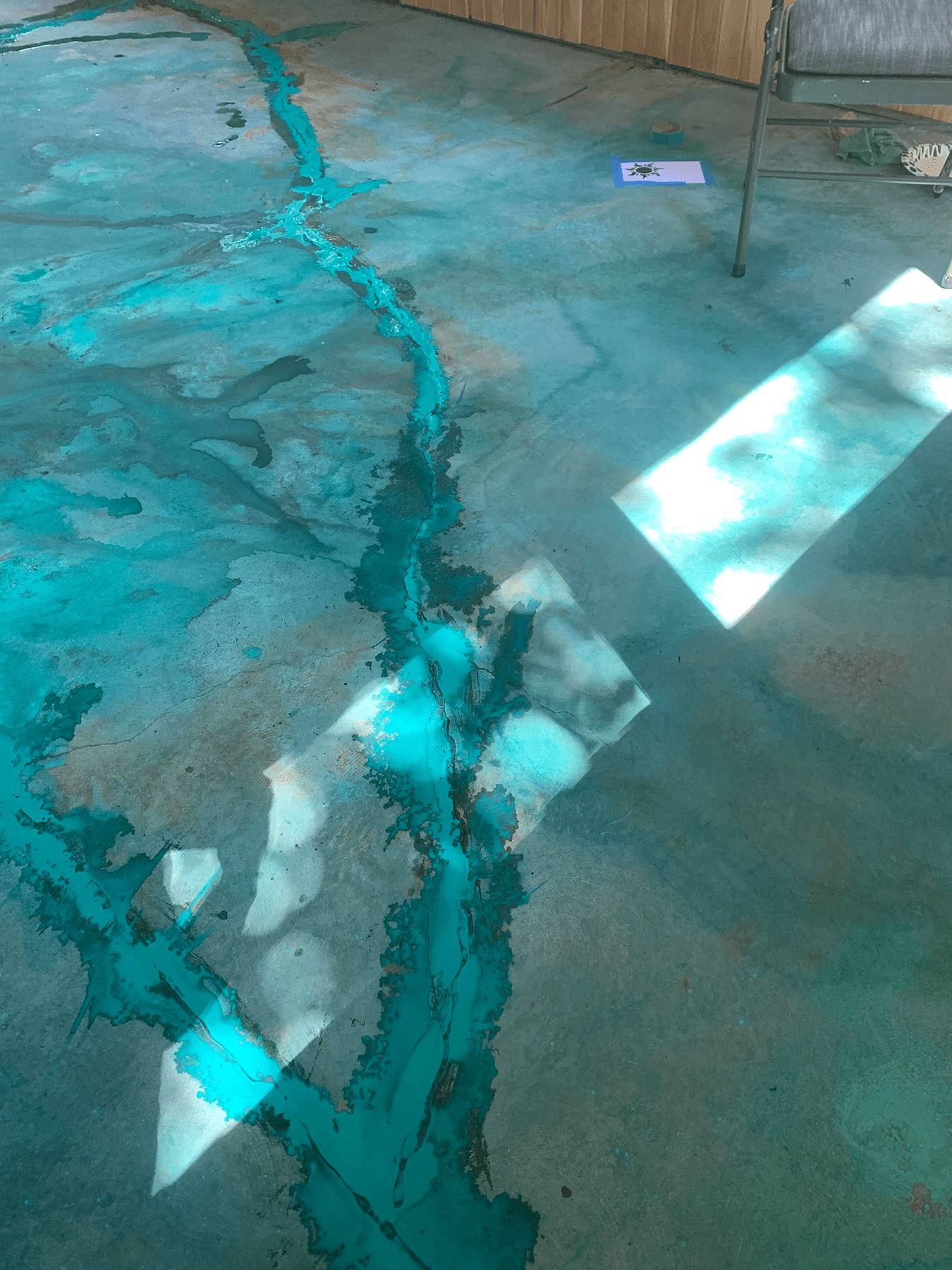 Close-up view of a major crack in the porch floor, artfully integrated into the design using blue and black acrylics and later filled with epoxy
