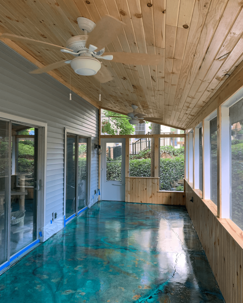 Sunroom concrete floor stained with Azure Blue, English Red, and Seagrass EverStain acid stains, then accented with teal, black, and cream acrylic paints