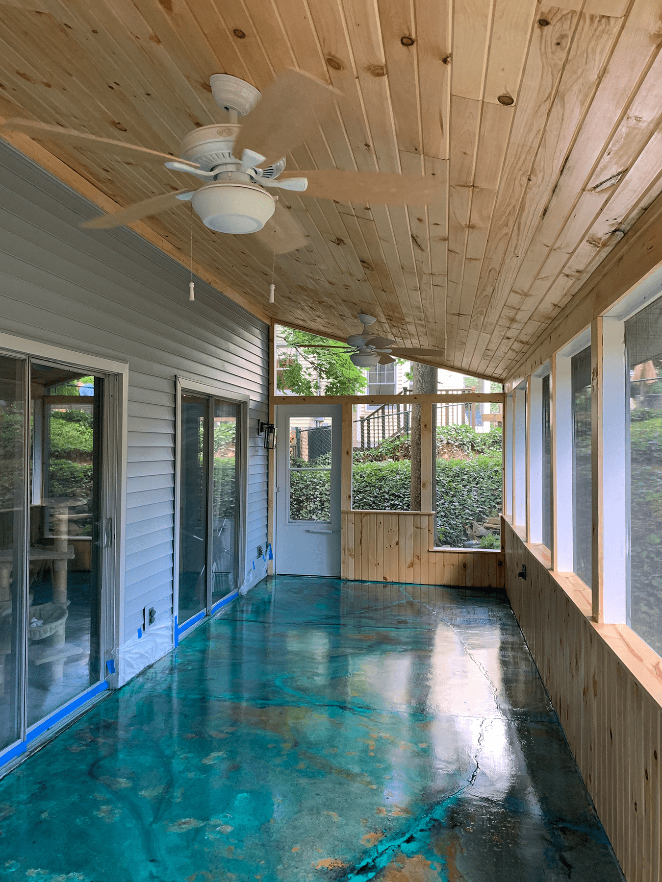 Sunroom concrete floor stained with Azure Blue, English Red, and Seagrass EverStain acid stains, then accented with teal, black, and cream acrylic paints