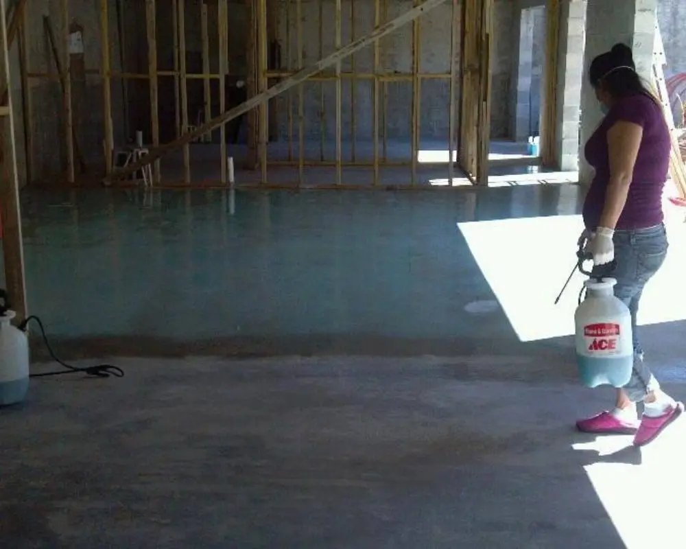 A woman applying Azure Blue Acid Stain to the concrete floor